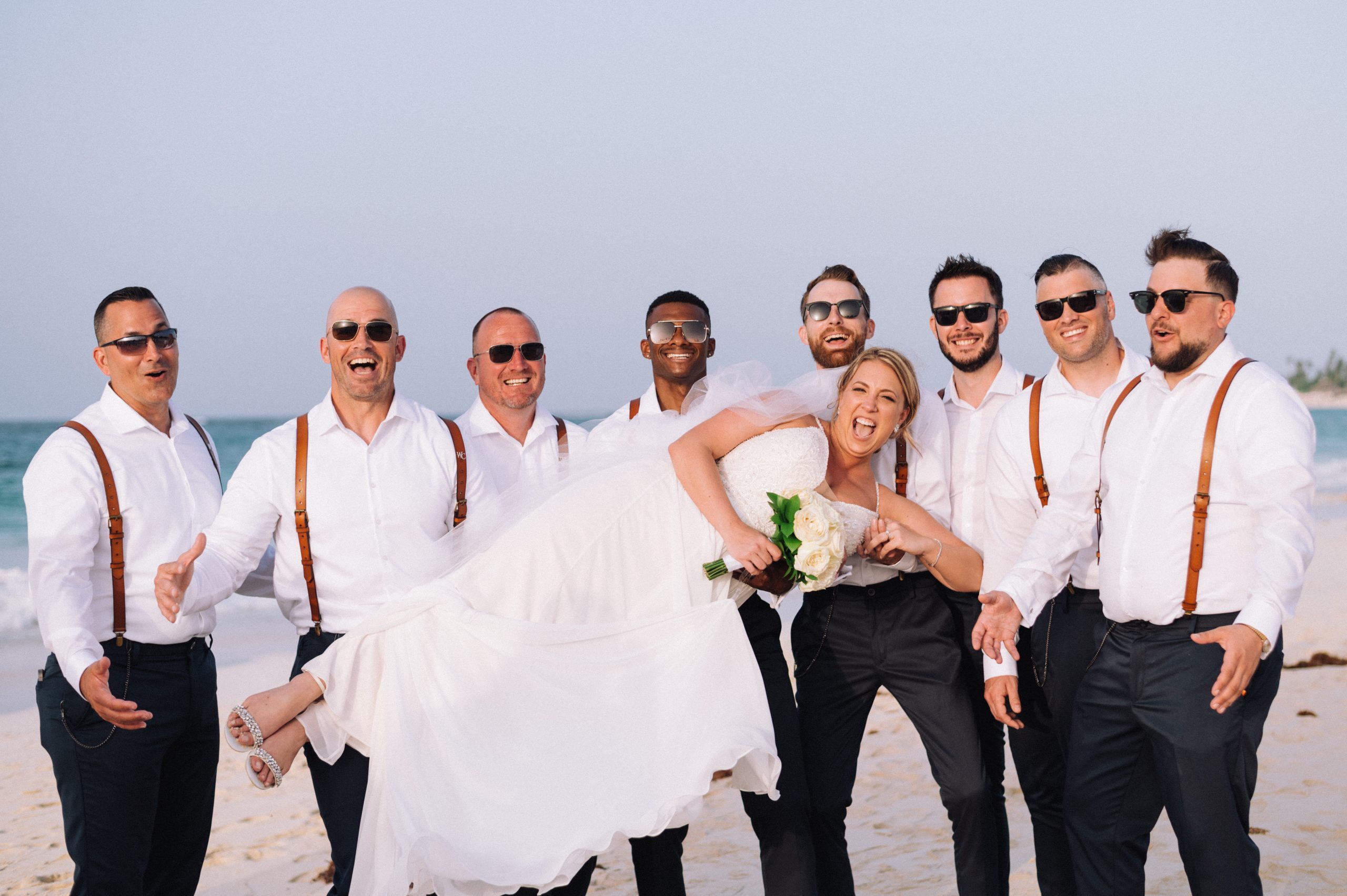 Groomsmen holding bride laying down while on Punta Cana beach