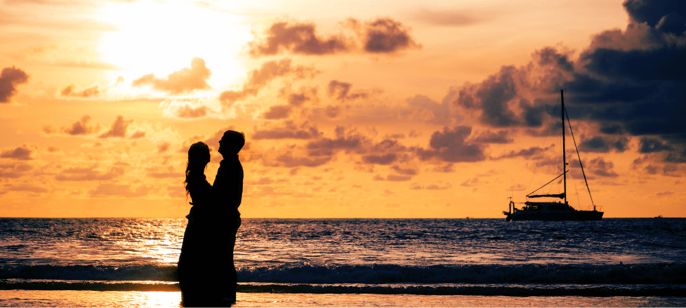 couple standing by the water during sunset