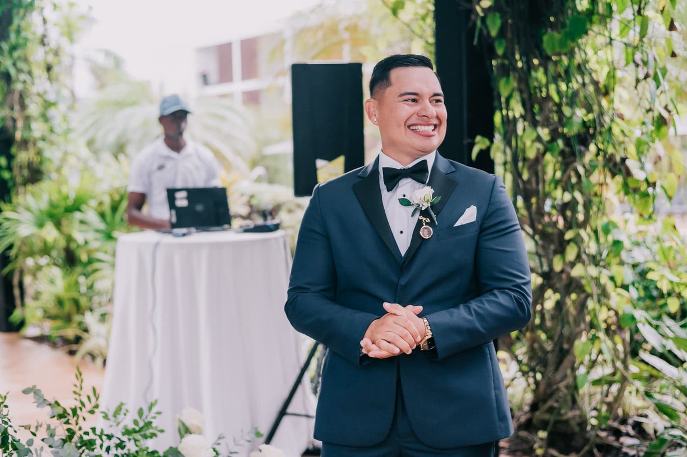 Elegant groom in tuxedo smiling at wedding ceremony.