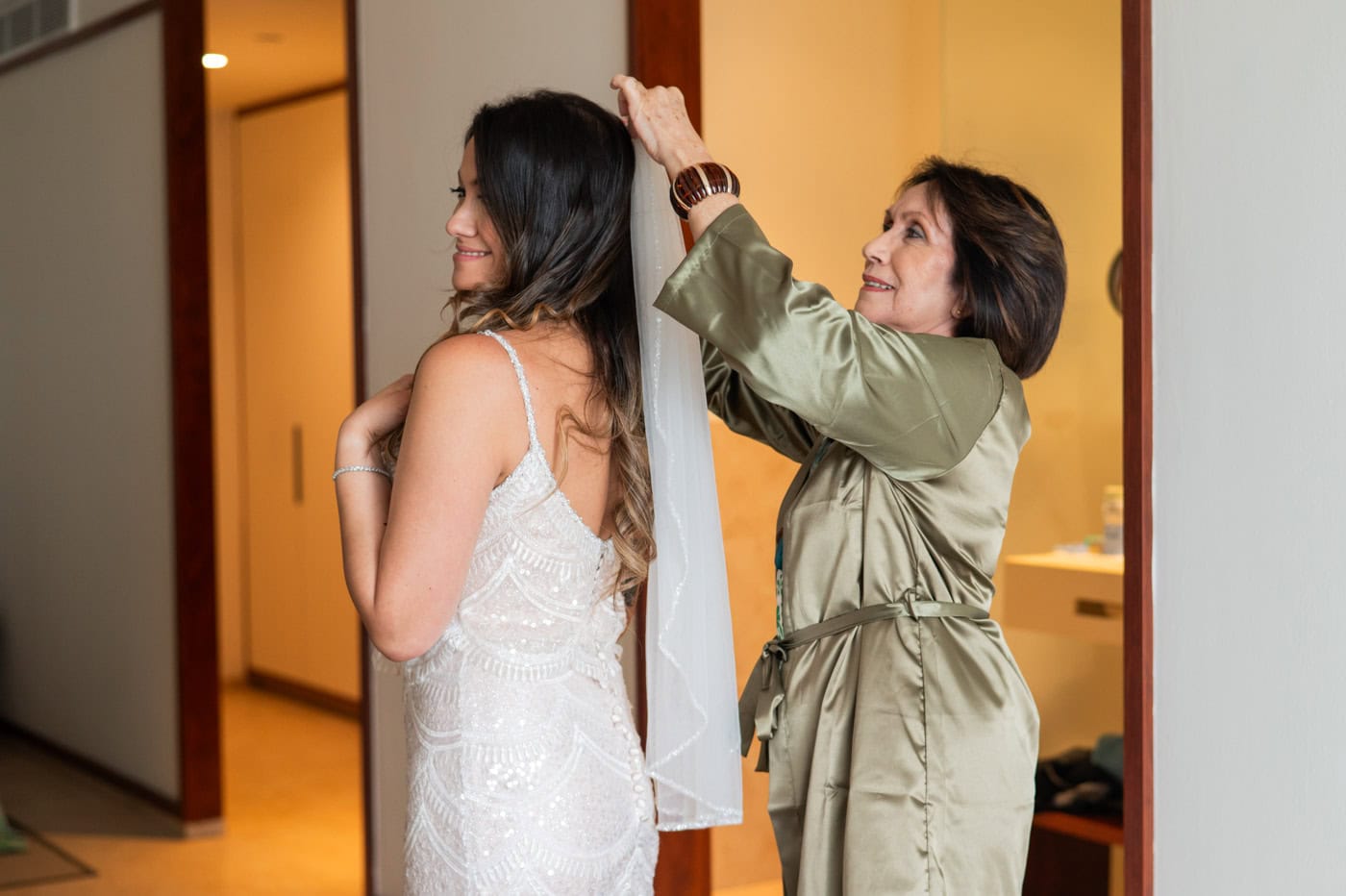 Wedding coordinator helping the bride adjust her veil in a hotel suite before the ceremony