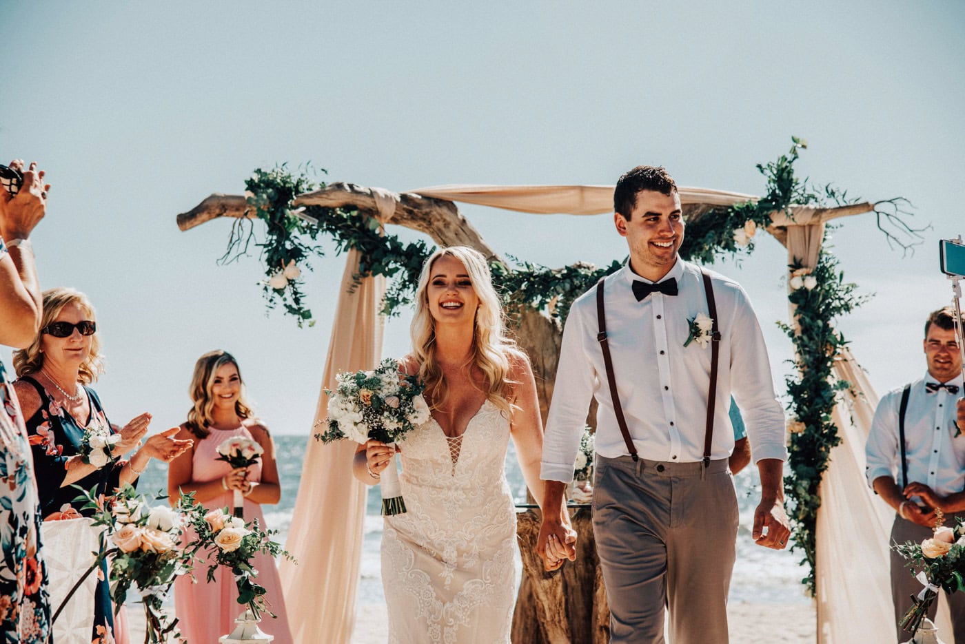 Bride and groom walking together among their wedding party at a beach wedding in Punta Cana