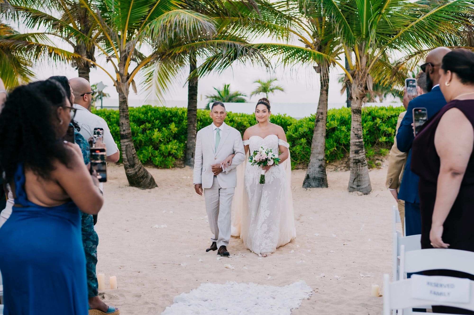 Bride and her father walking down the sandy aisle as guests look on at Dreams Onyx Punta Cana