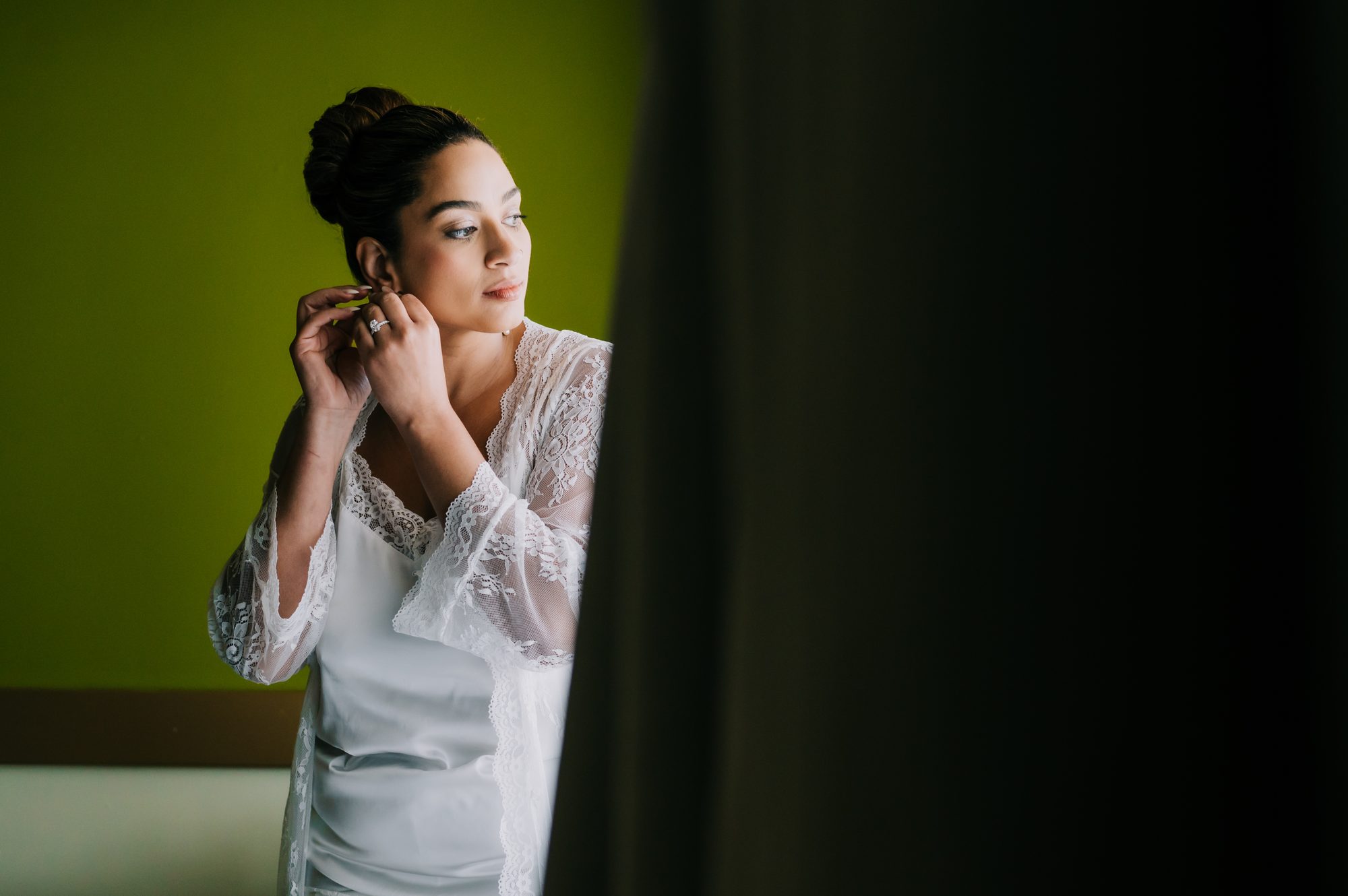 Bride in a lace robe fastening her earring during bridal prep at Dreams Onyx Punta Cana