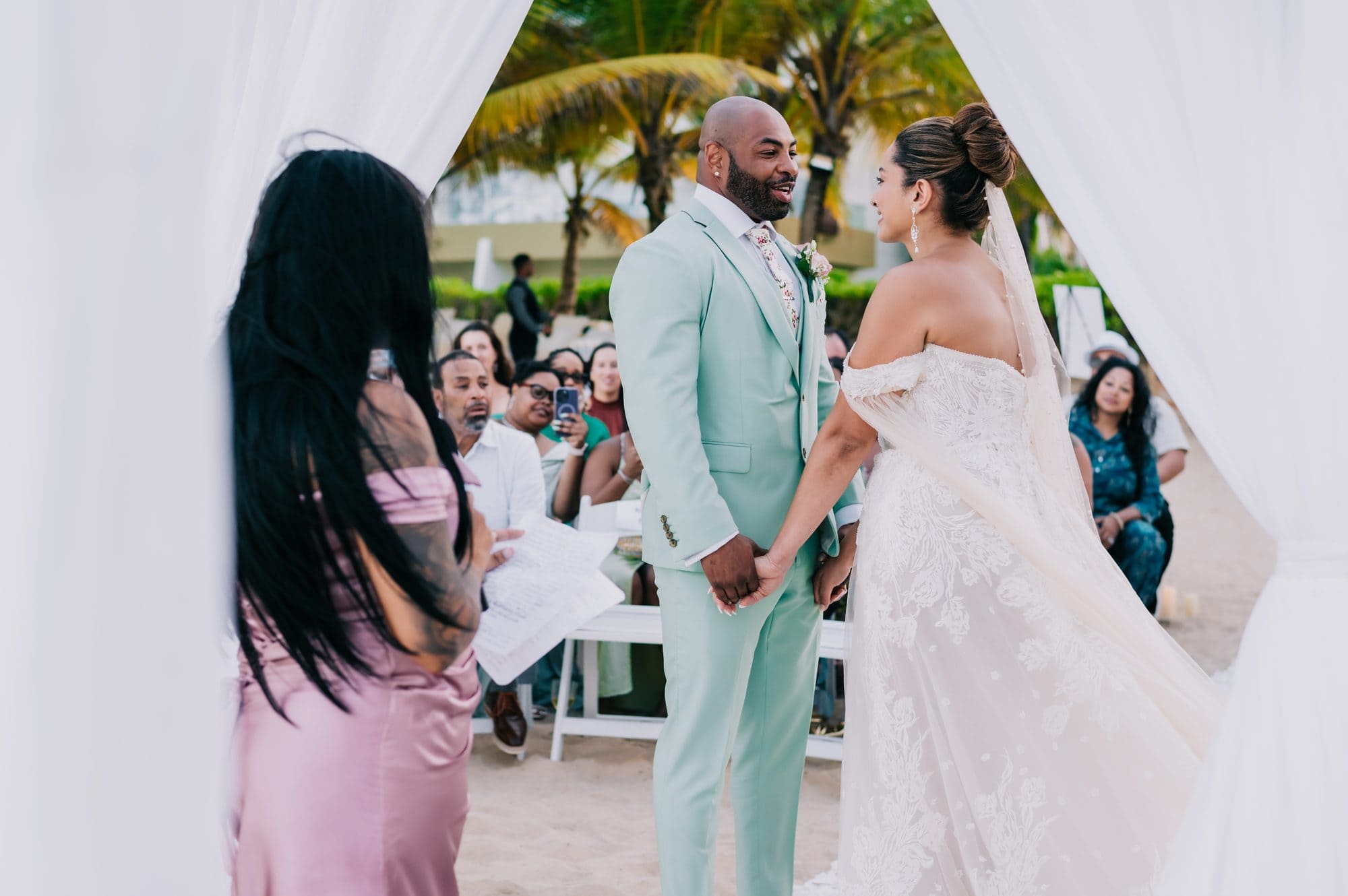Bride and groom holding hands at the beachfront altar during their Dreams Onyx wedding ceremony