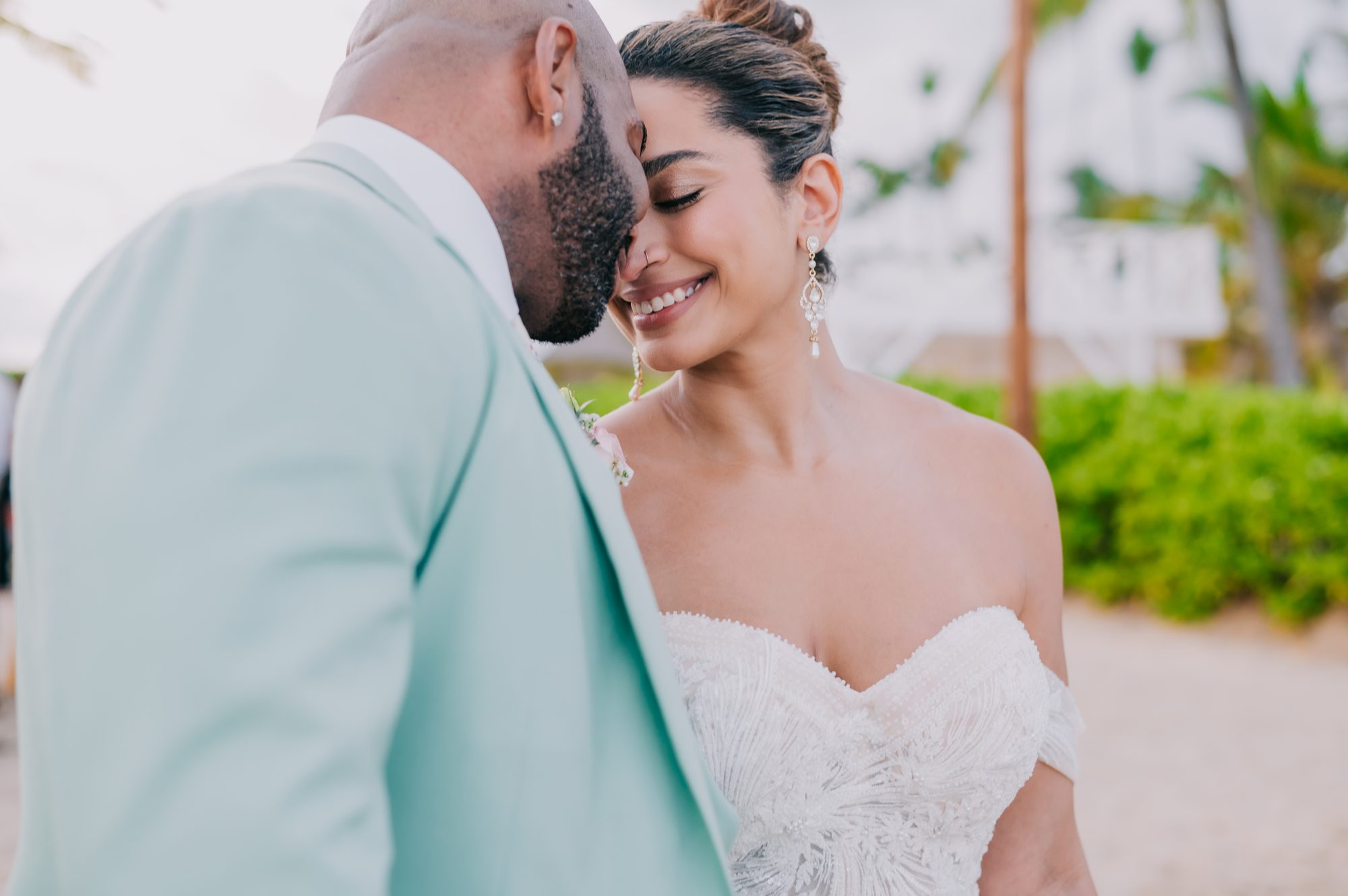 Bride smiling with eyes closed as the groom rests his forehead on hers during beach portraits at Dreams Onyx