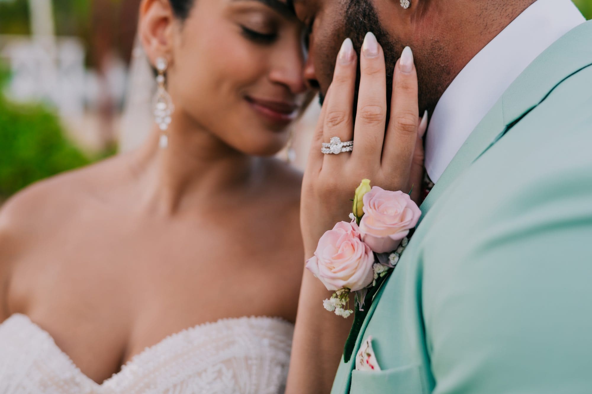 Close-up of the bride’s wedding rings as she rests her hand on the groom’s cheek