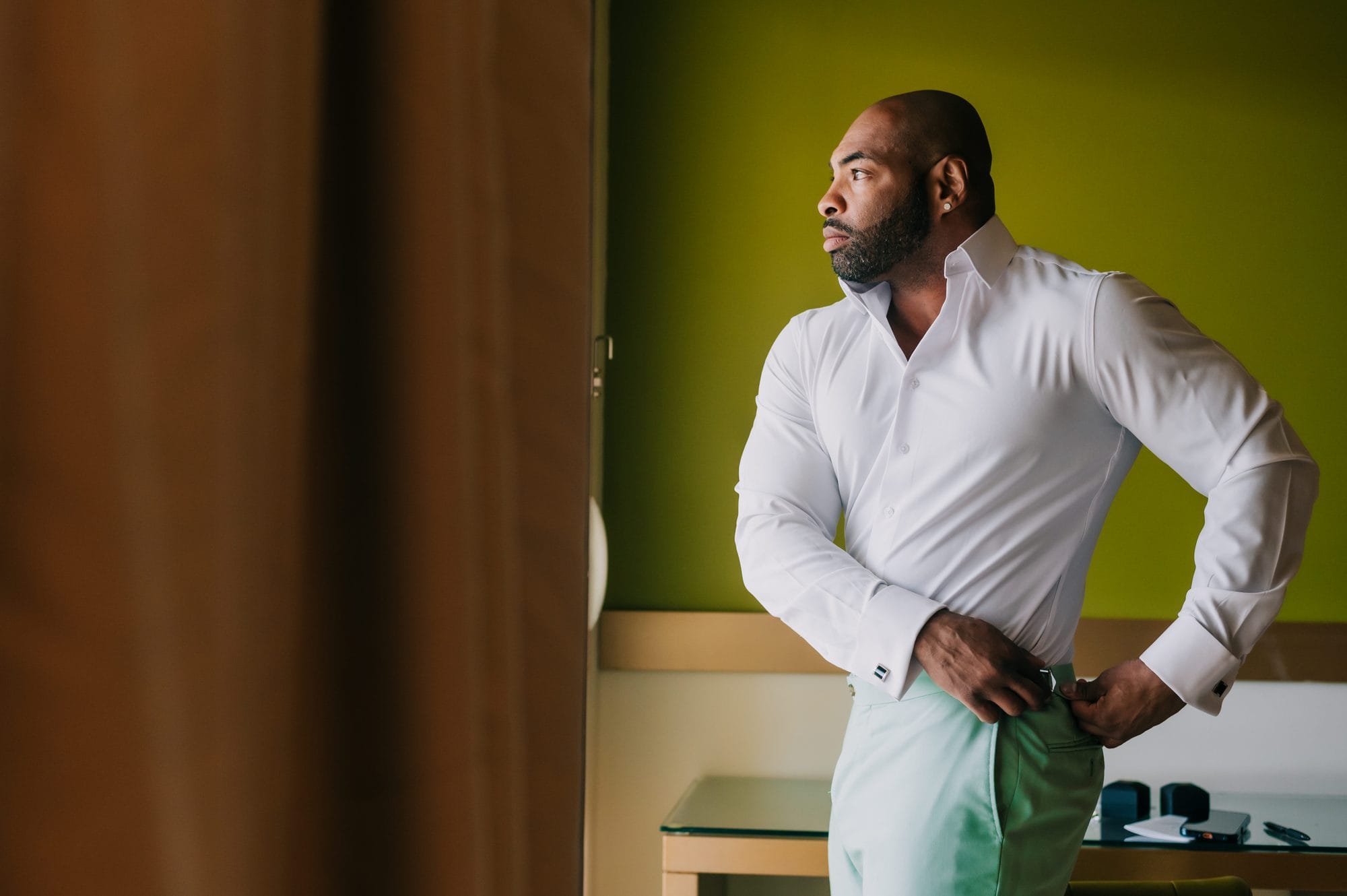 Groom in mint trousers getting ready by the window for his Dreams Onyx wedding in Punta Cana