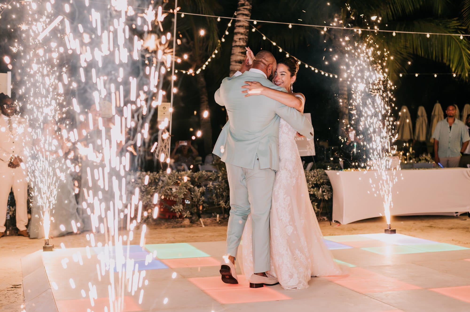 Bride and groom embracing during their first dance framed by sparkler fountains at a Punta Cana beach reception