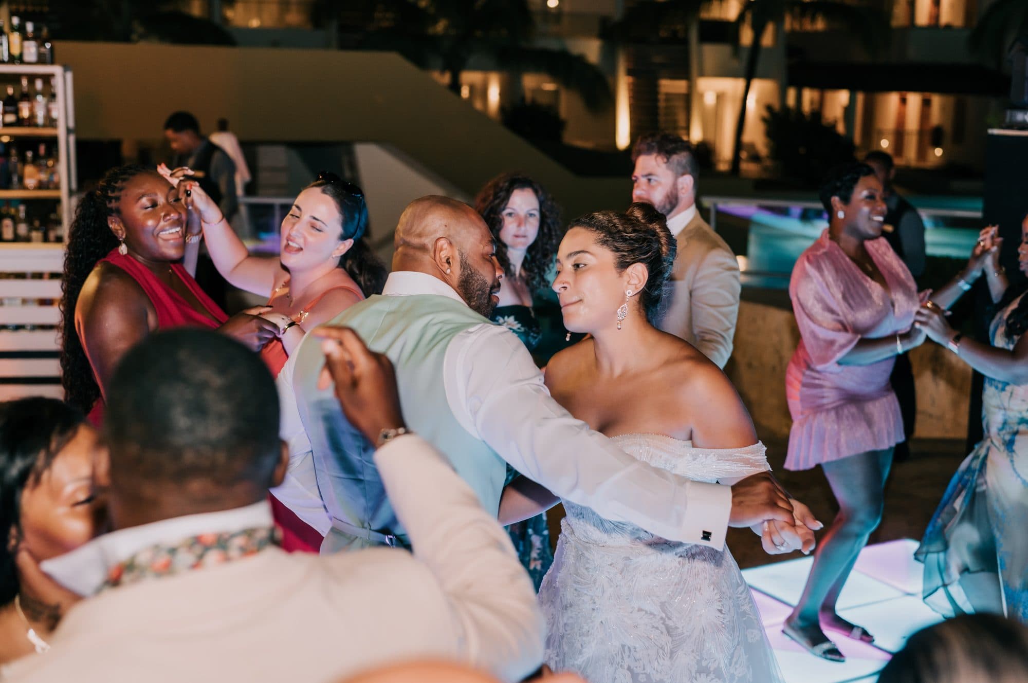 Bride and groom celebrating on a packed dance floor with guests at their Dreams Onyx wedding reception