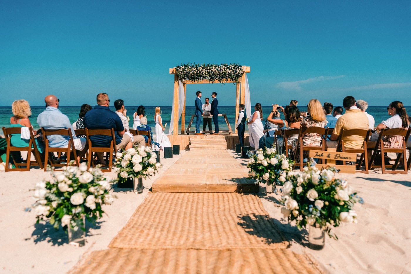 A beachfront ceremony beneath a floral arch marks the central moment of a Punta Cana destination wedding timeline.