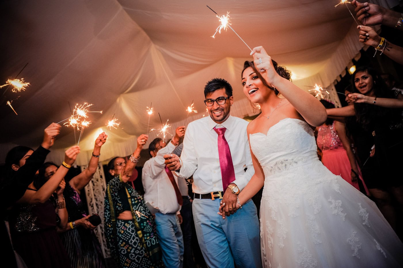 Newlyweds celebrate on the reception dance floor with friends and glowing sparklers at their Punta Cana wedding.