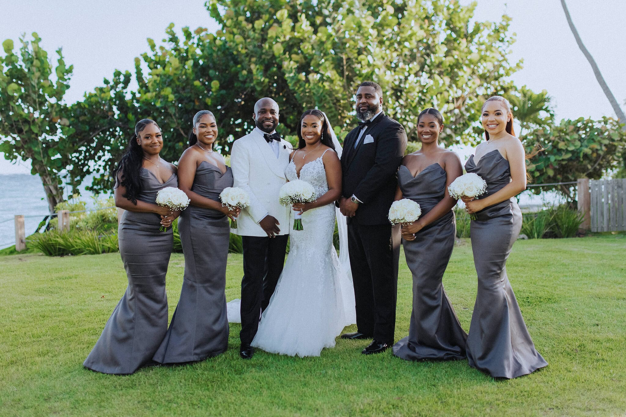 Bride and groom with close family for a group photo by the sea at a destination wedding