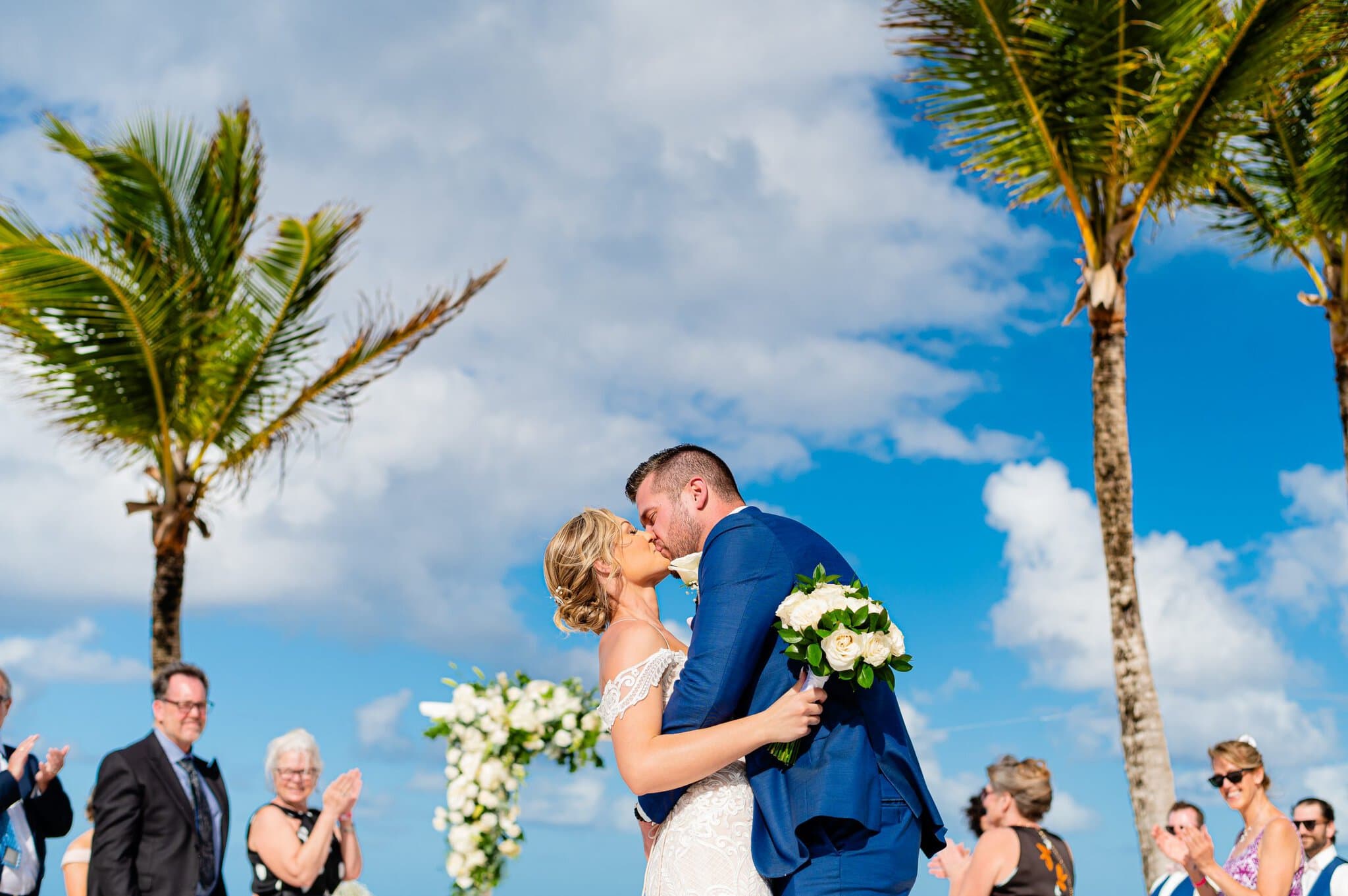 Bride and groom kiss on the beach under palm trees at their Punta Cana wedding