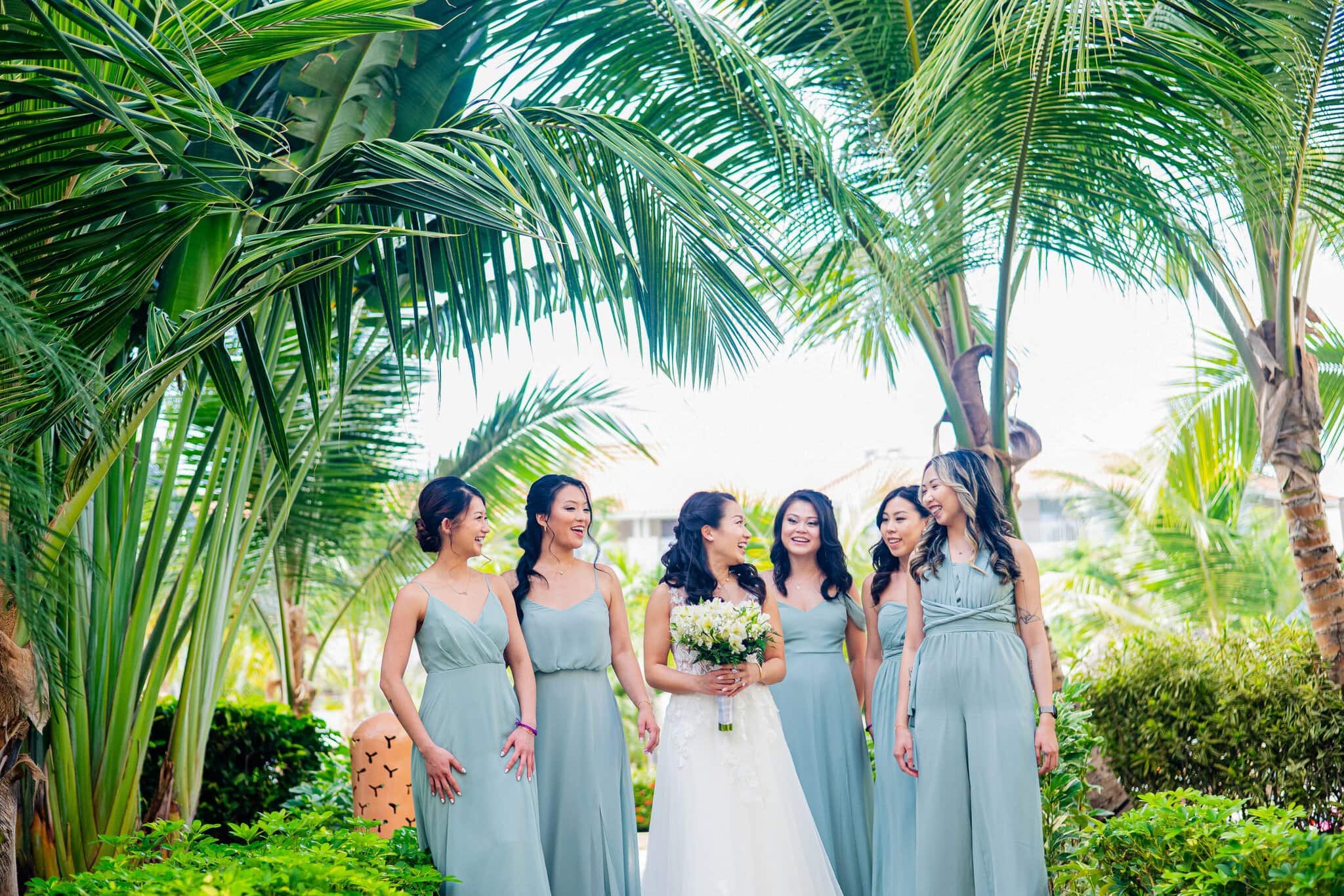 Bride laughing with her bridesmaids under palm trees at a Punta Cana destination wedding