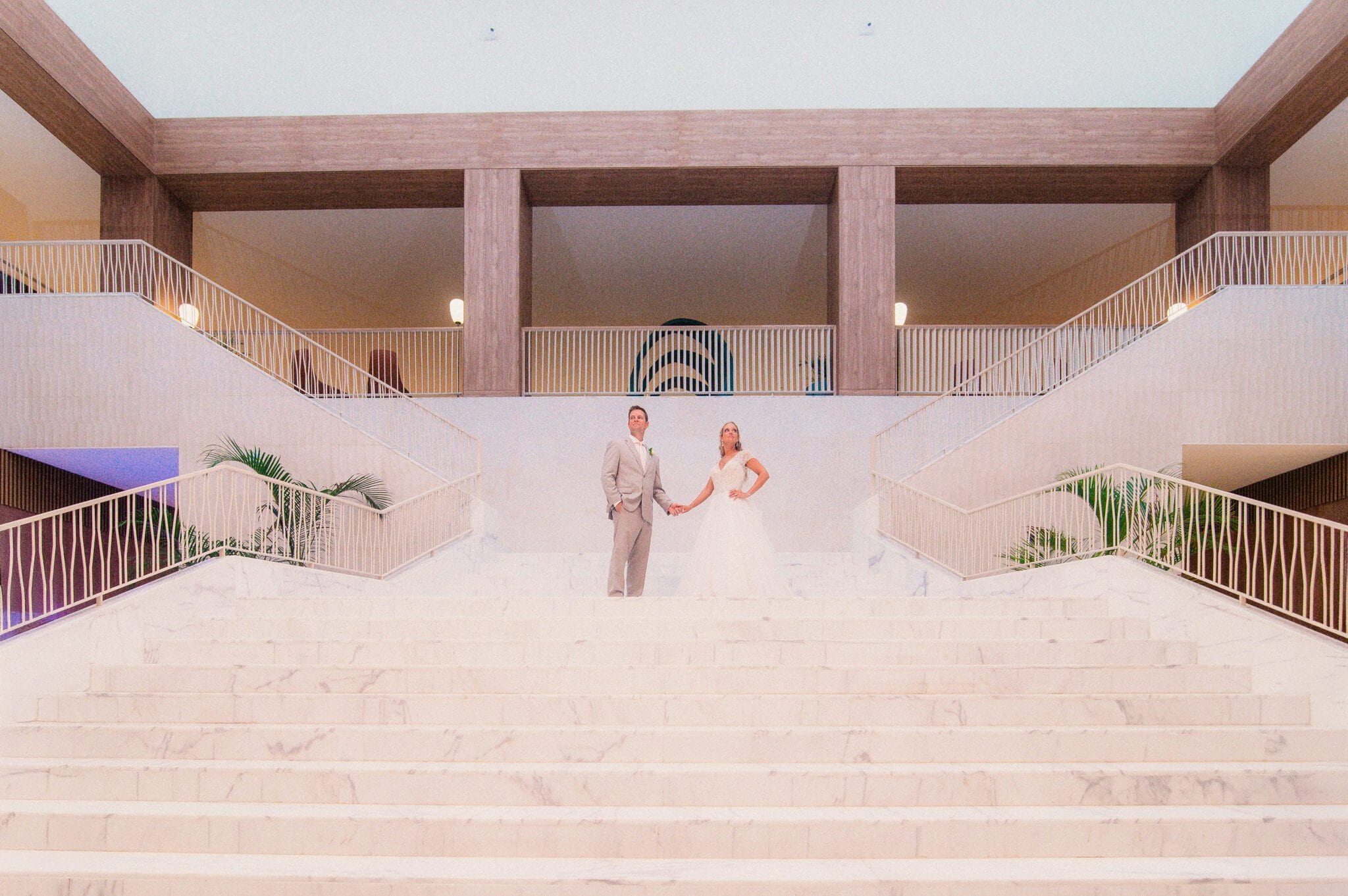 Bride and groom holding hands on a grand marble staircase at a Punta Cana resort