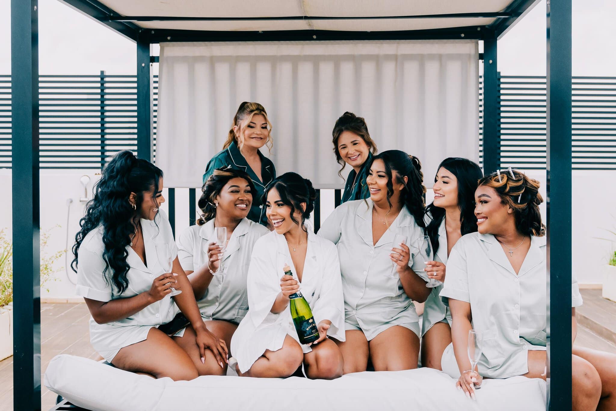 Bride and bridesmaids laughing in matching robes with champagne before a Punta Cana wedding