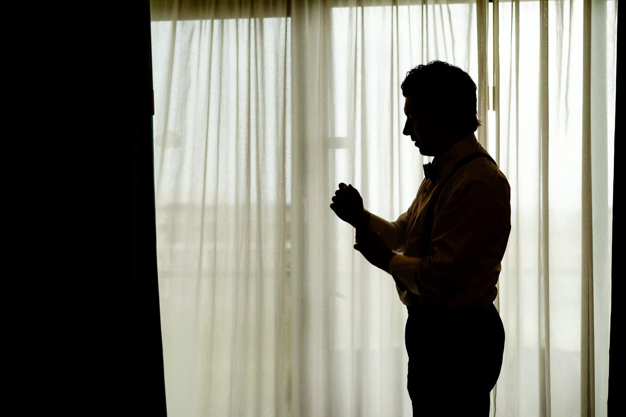 Silhouette of a groom getting ready by a window before his Punta Cana wedding