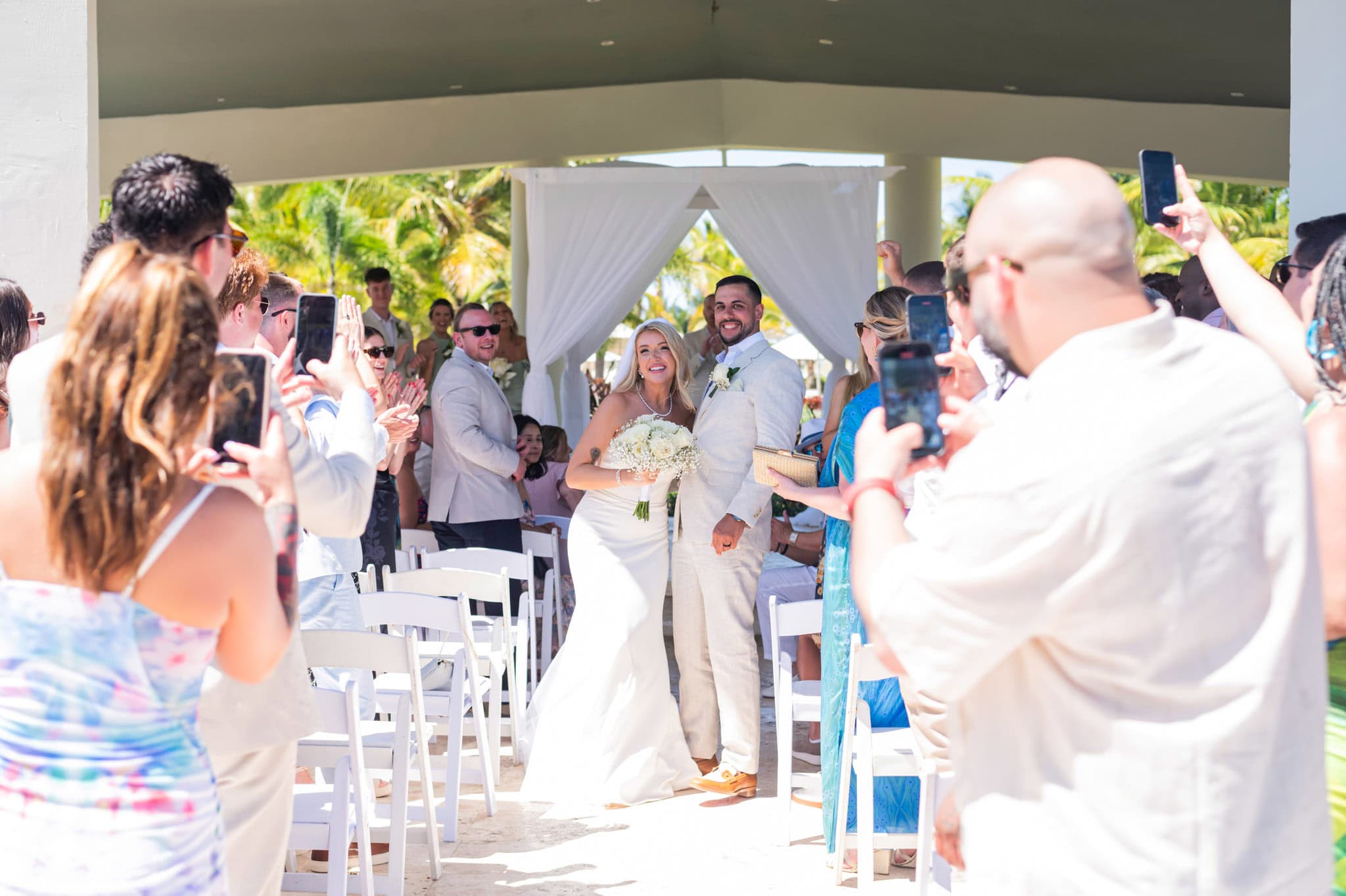 Wide view of the newlyweds celebrating as guests surround a modern resort ceremony pavilion.