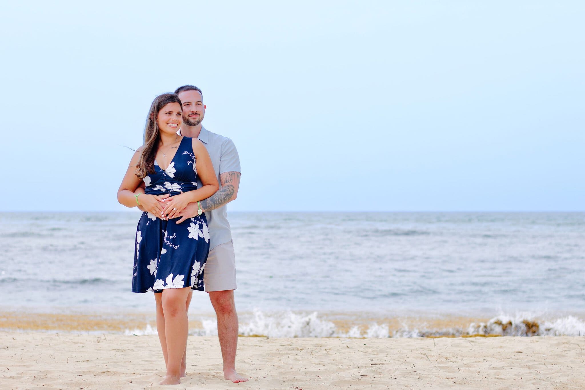 Engaged couple embracing at the water edge as the sun goes down