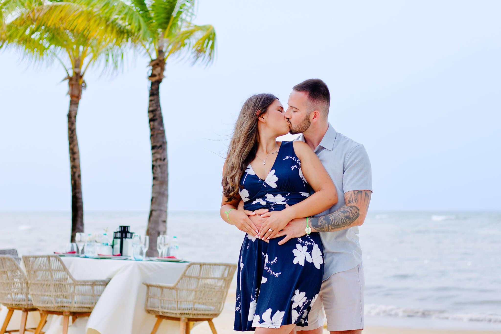 Newly engaged couple kissing under the palms beside their beach dinner at Live Aqua Punta Cana