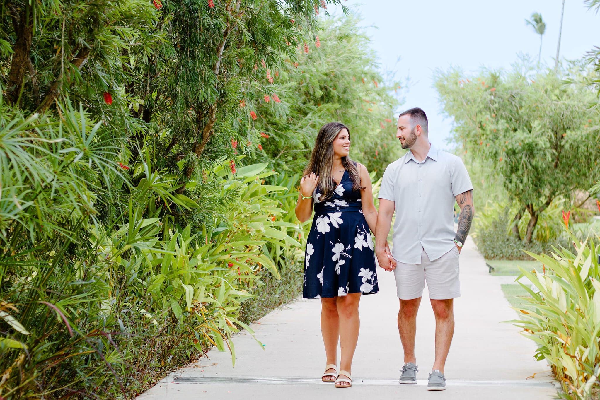 Newly engaged couple walking hand in hand down a tropical garden path at Live Aqua Punta Cana