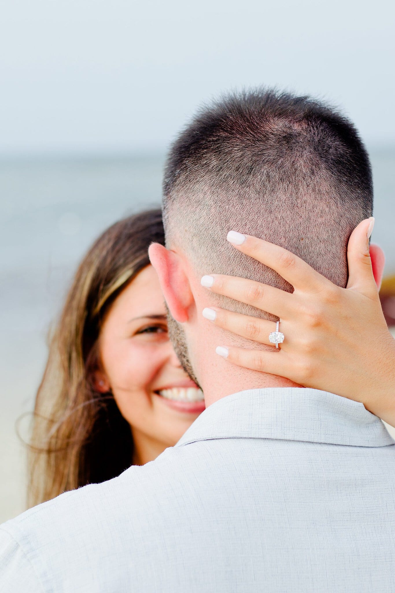 Close-up of an engagement ring on the hand of a newly engaged woman embracing her fiance