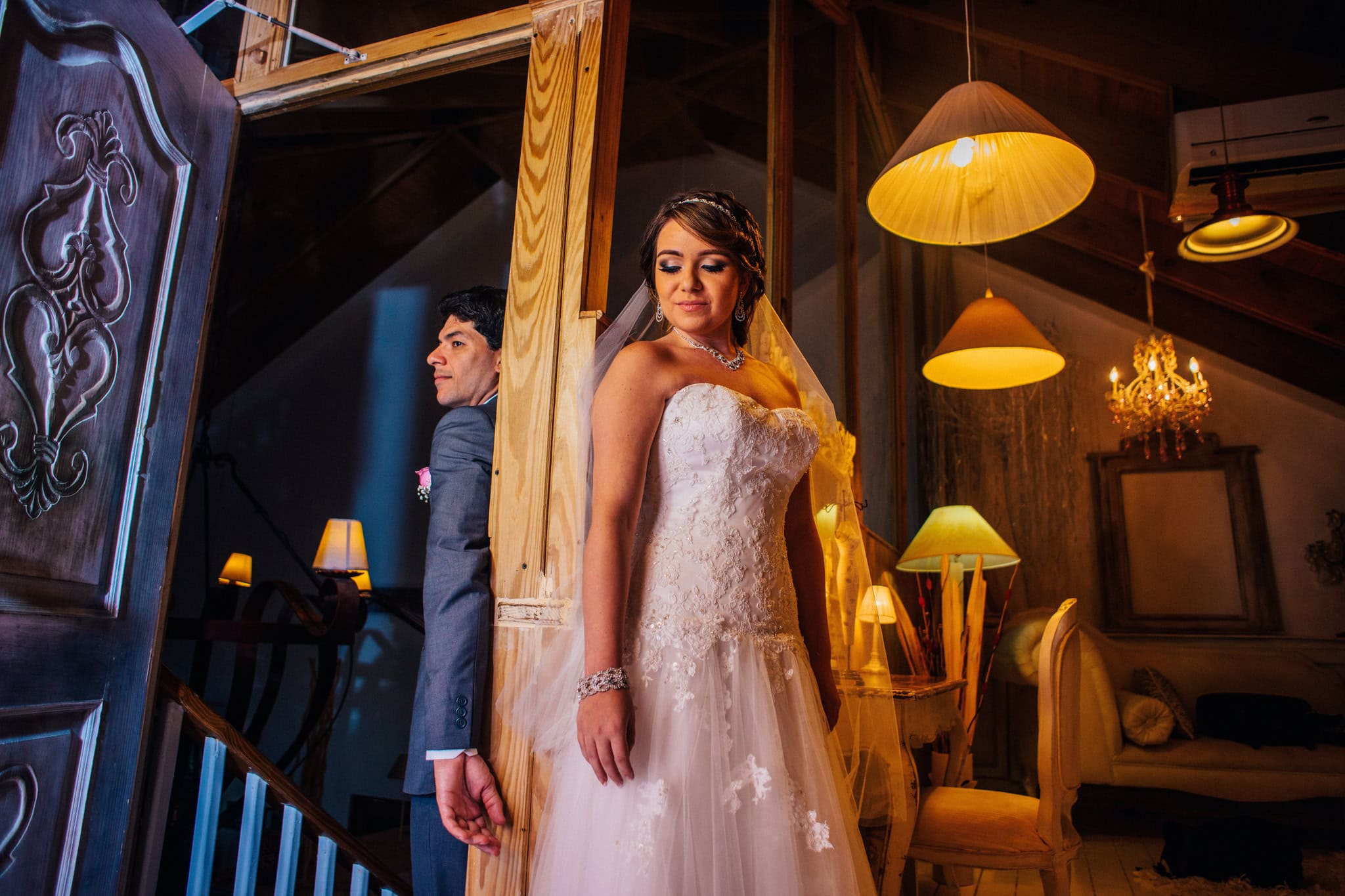 Bride in her gown waiting by the stairs with the groom behind her before the ceremony at Kukua Beach Club, Punta Cana