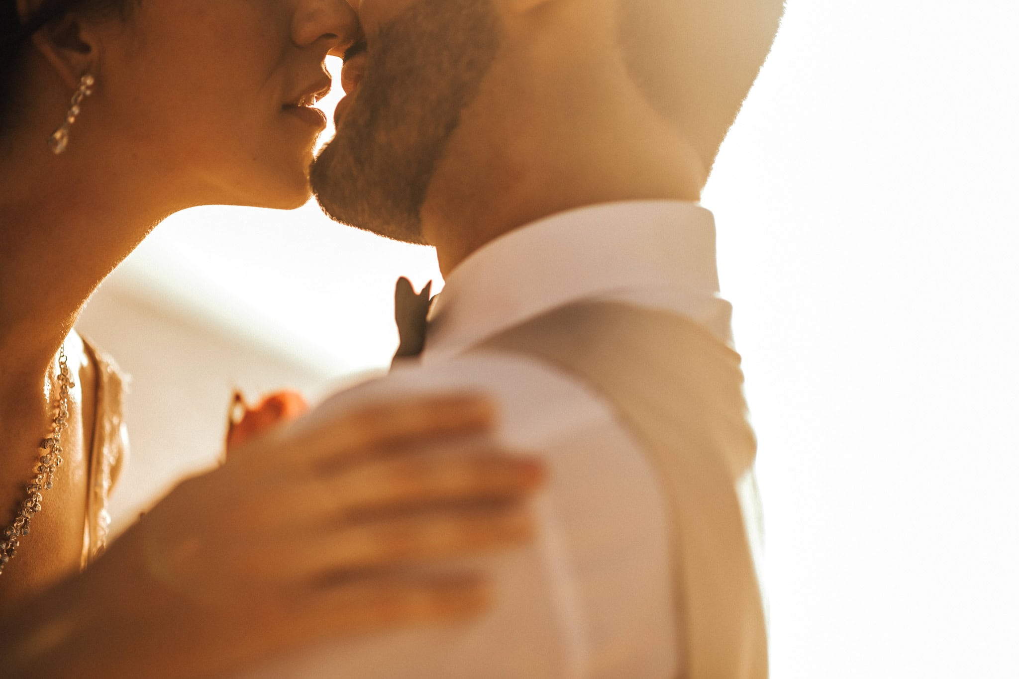 Bride and groom leaning in for a kiss in warm backlight, her hand resting on his shoulder, at a Dominican Republic wedding