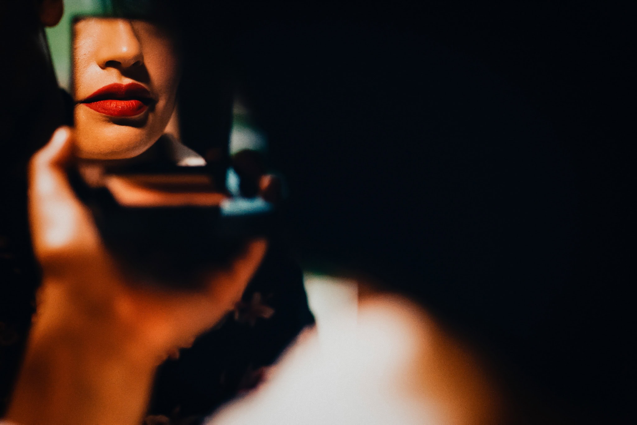 Bride's face reflected in a mirror as she puts on red lipstick before her wedding at Kukua Beach Club, Punta Cana