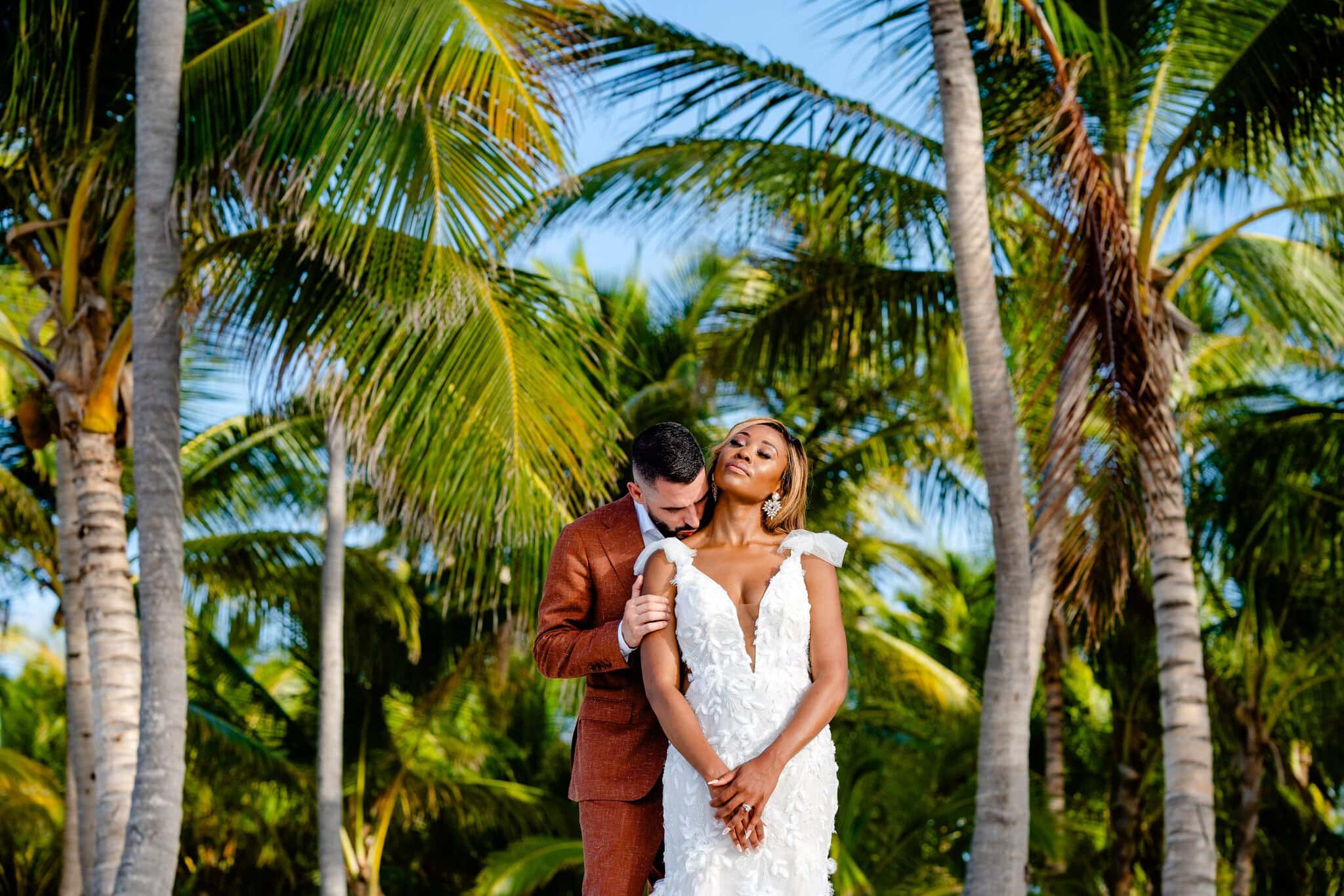 Newlyweds posing beneath tall palm trees during a wedding portrait in Cabeza de Toro