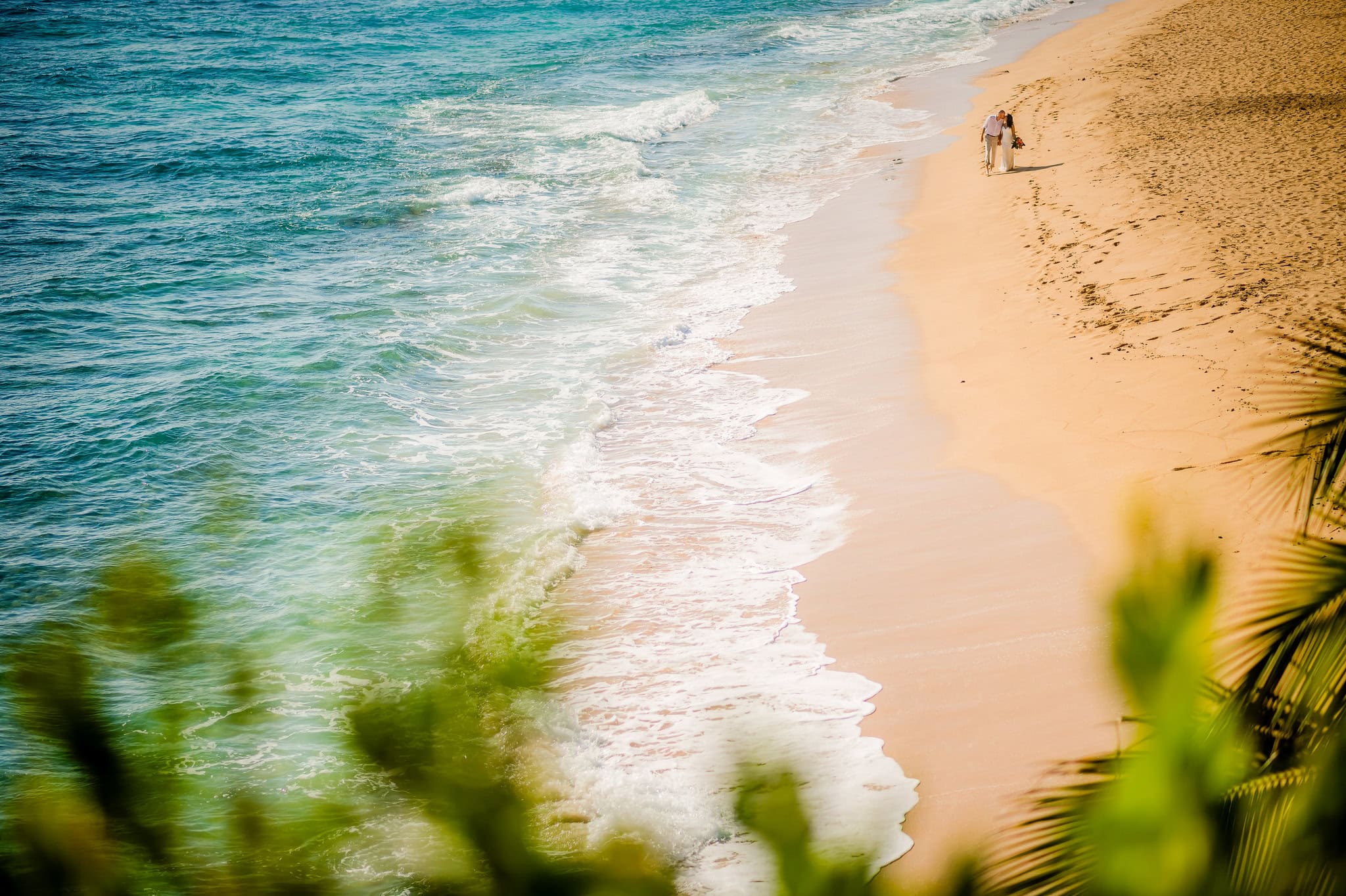Bride and groom walking alone along the shoreline of an empty beach in Cabrera, Dominican Republic