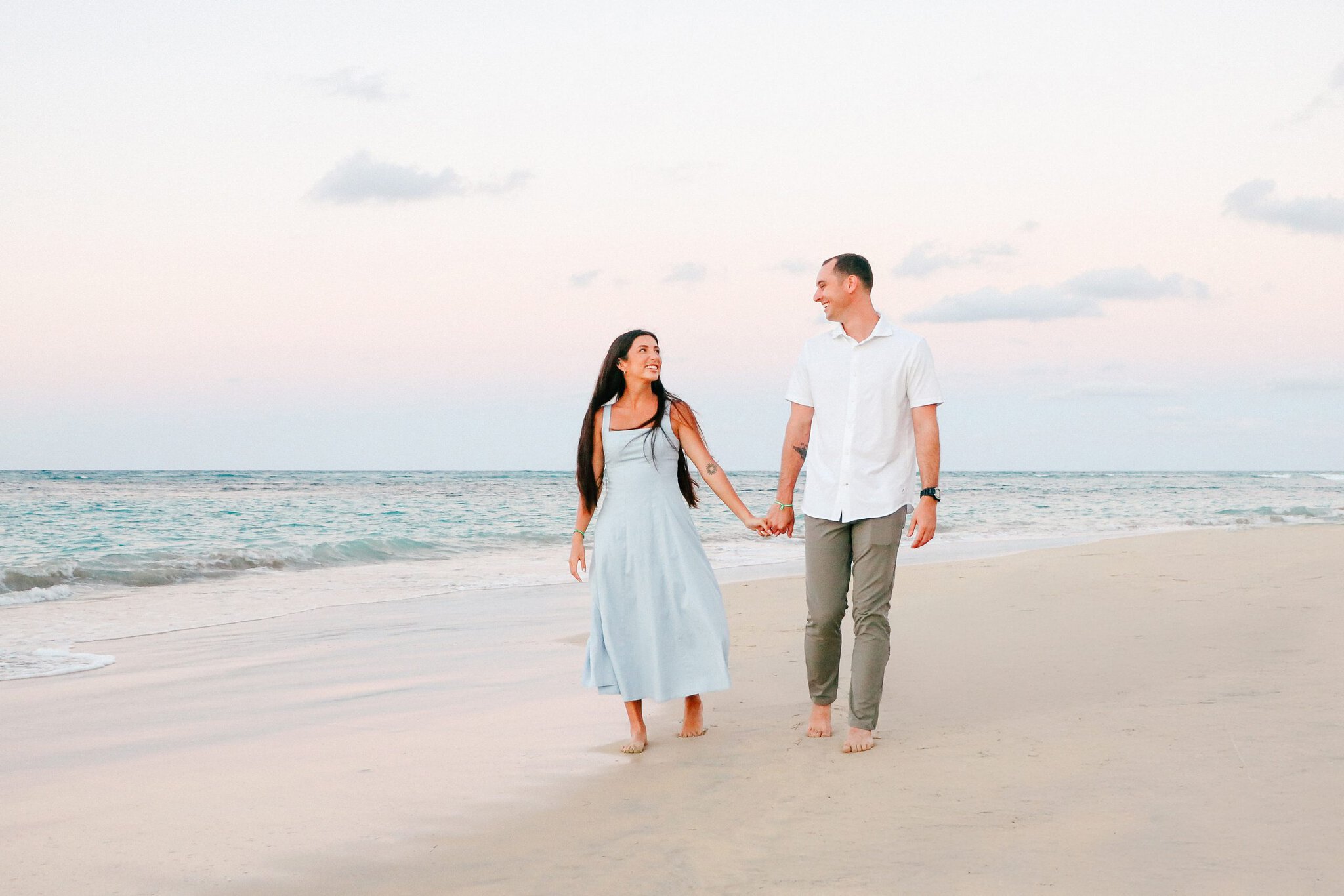 Couple holding hands and walking barefoot along the beach