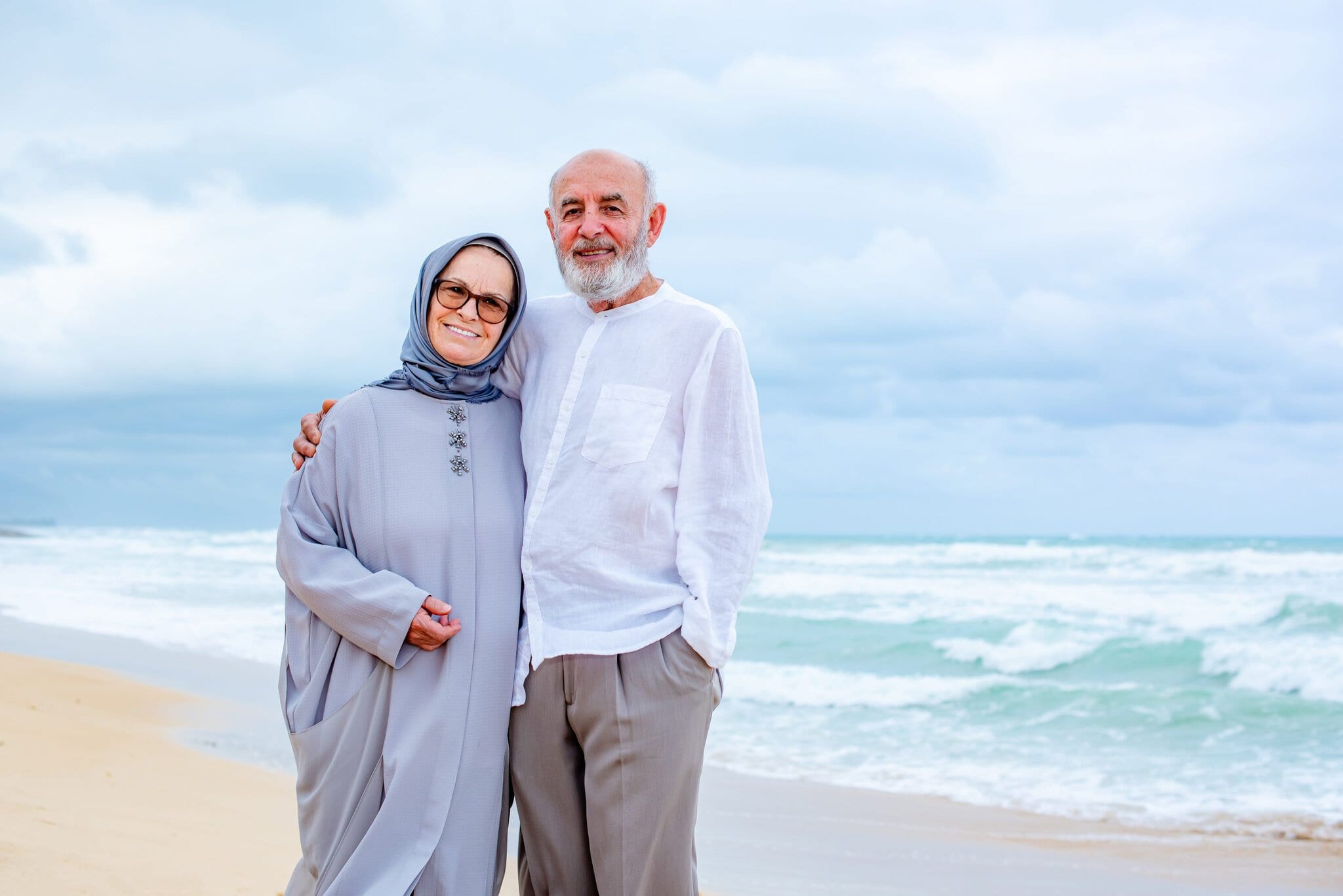Couple standing close together and smiling during a relaxed beach portrait session