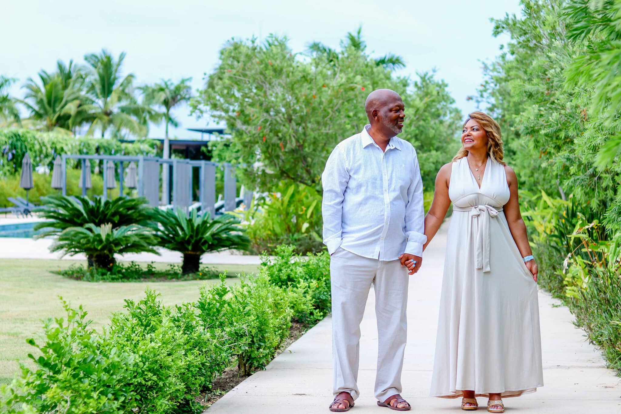 Couple holding hands and smiling at each other while walking through a tropical garden