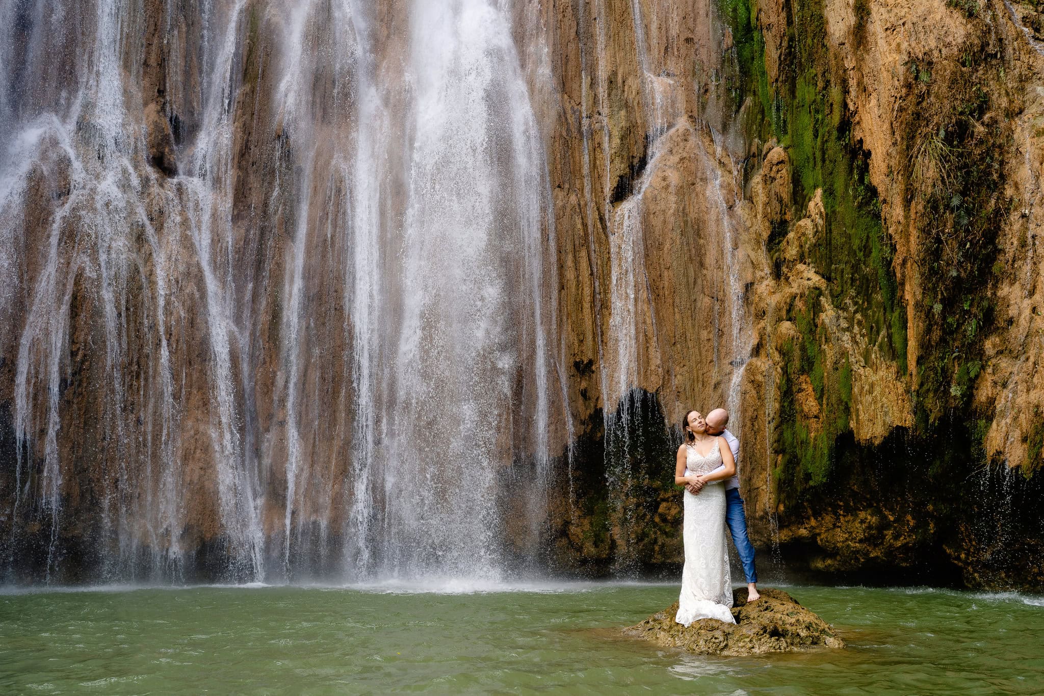 Bride and groom standing on a rock at the foot of El Limon waterfall near Las Terrenas, Dominican Republic