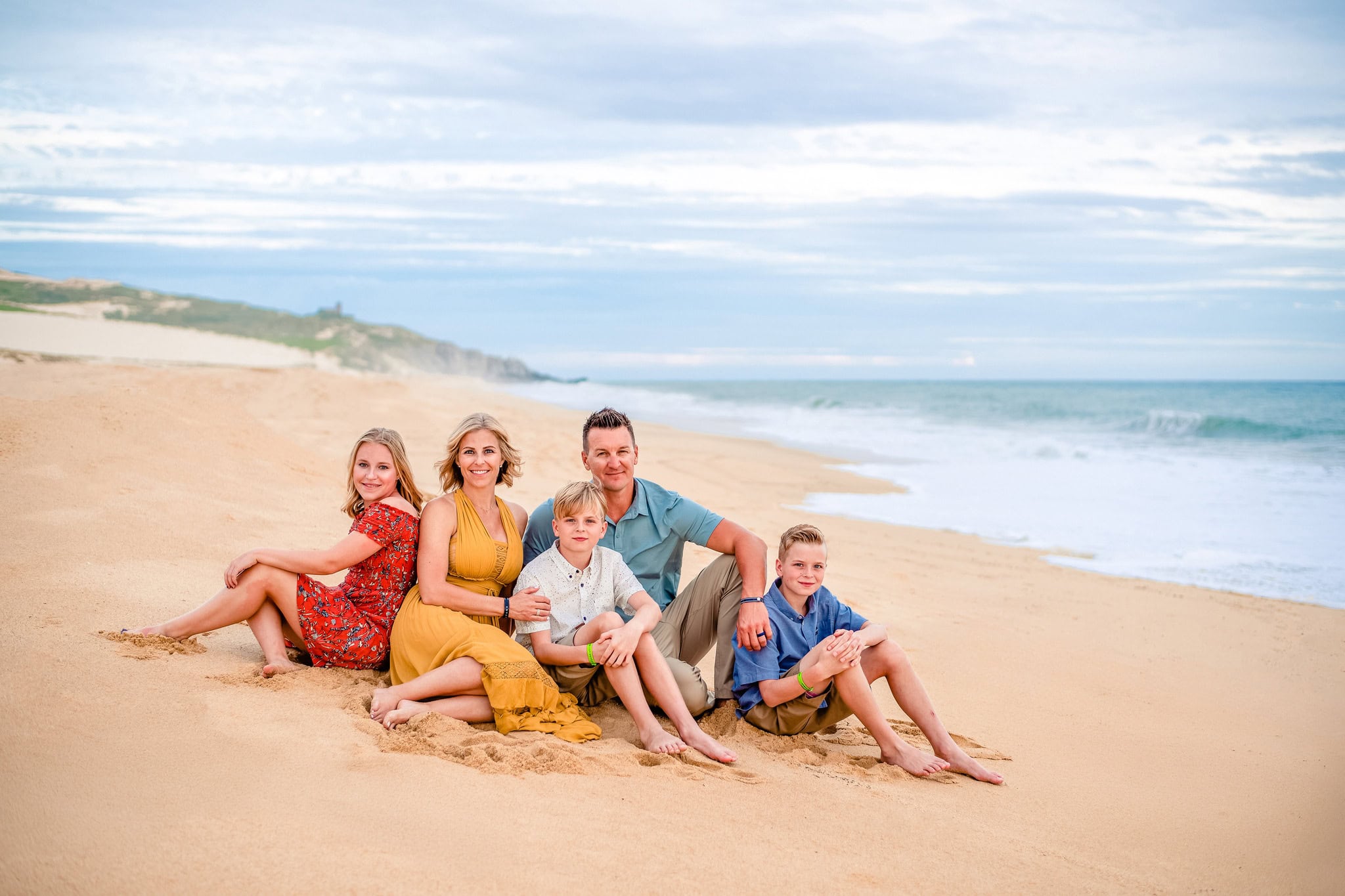 Family of five sitting together on the sand during a beach family photo session