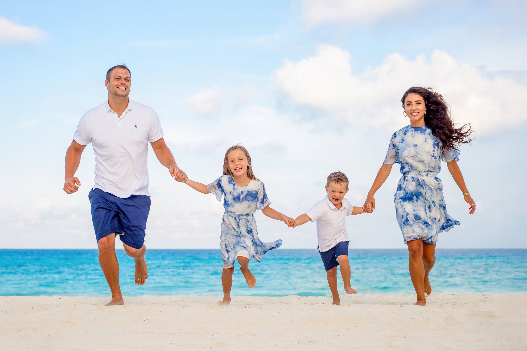 Family of four running along the beach during a family photo session in Punta Cana