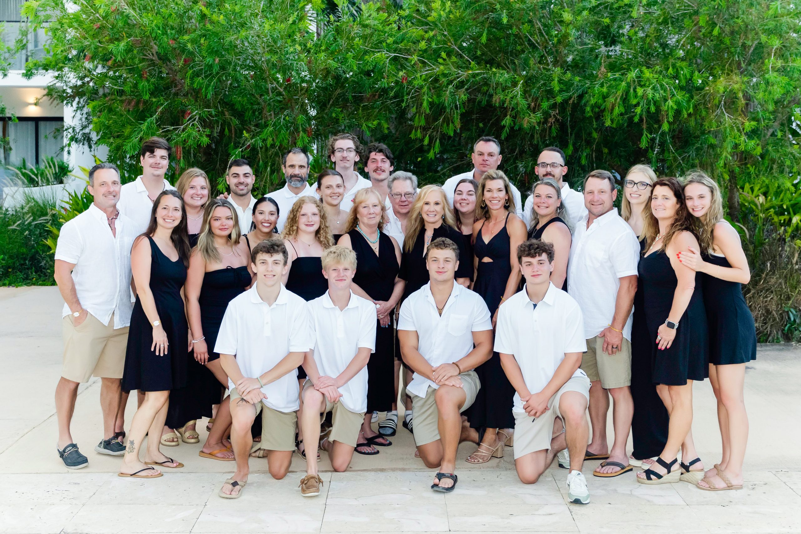 Large multi-generational family posing together in black and white outfits during a group portrait session in Bayahibe