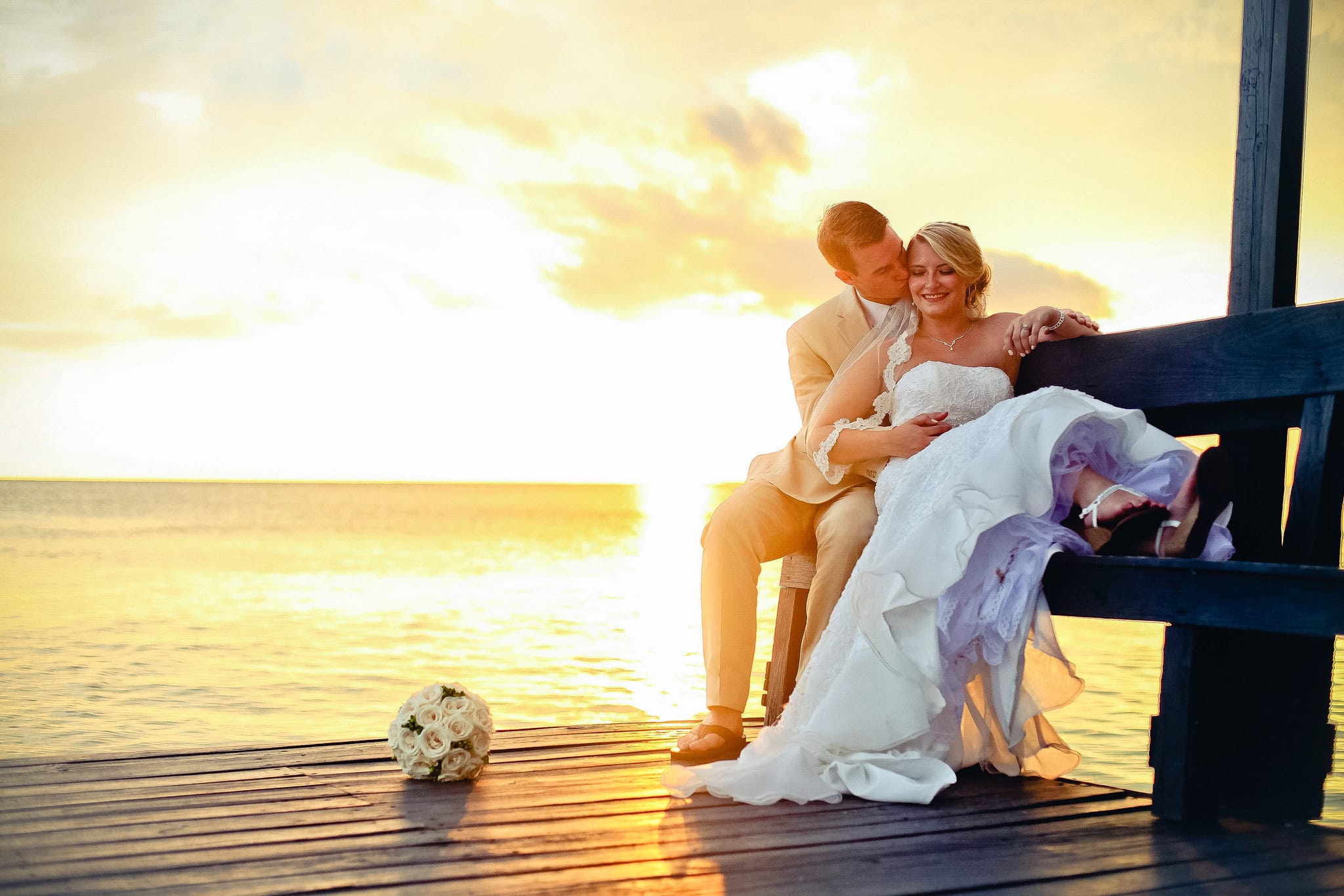 Bride and groom sitting together on a wooden pier at sunset after their wedding in La Romana, Dominican Republic