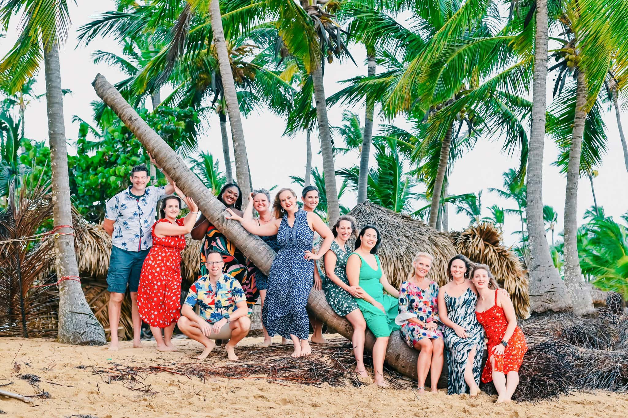 Large family group posing together beneath palm trees during a relaxed beach photo session