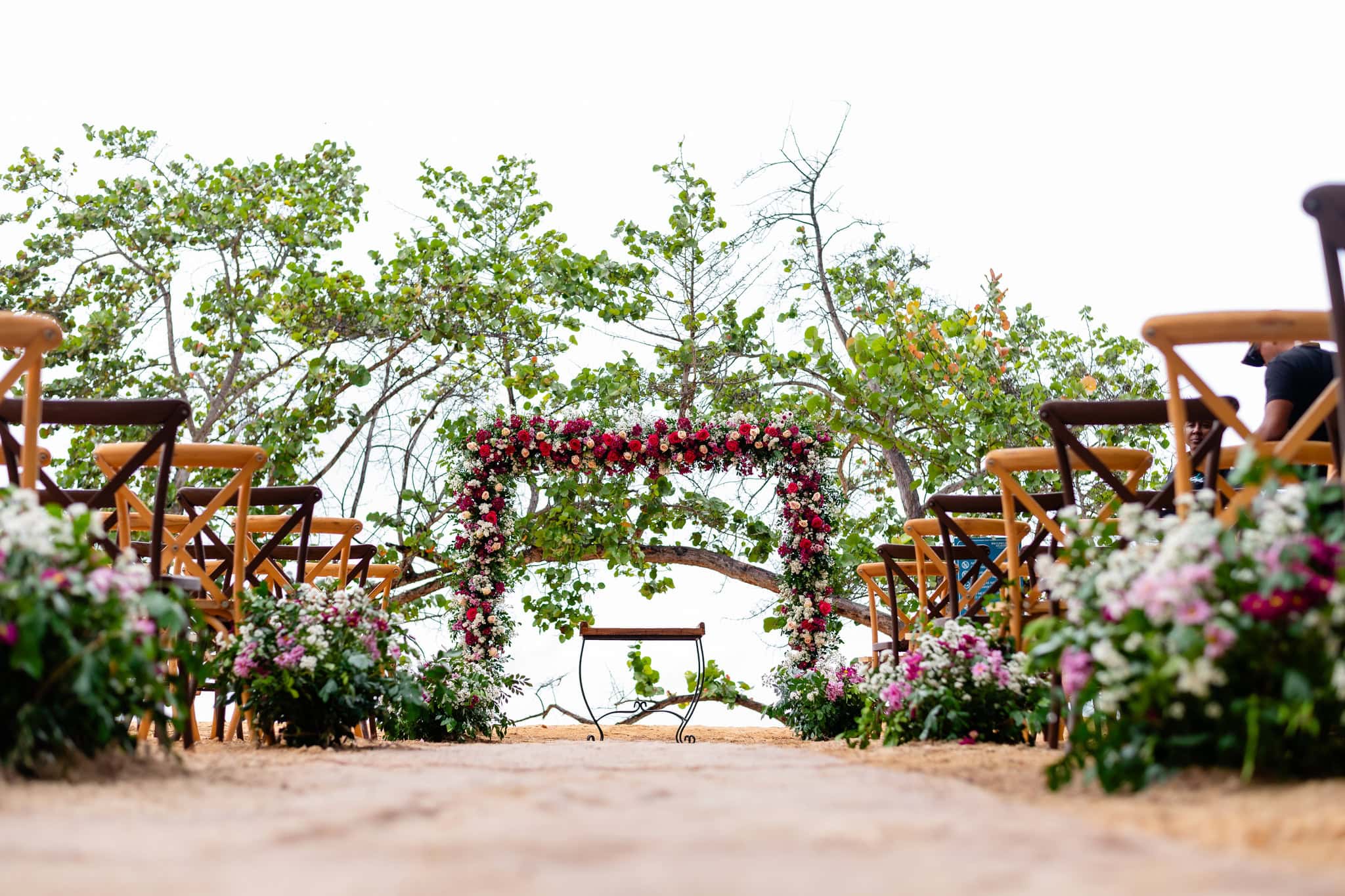 Wedding ceremony set up on the beach in Las Terrenas with a flower arch and wooden chairs, Dominican Republic