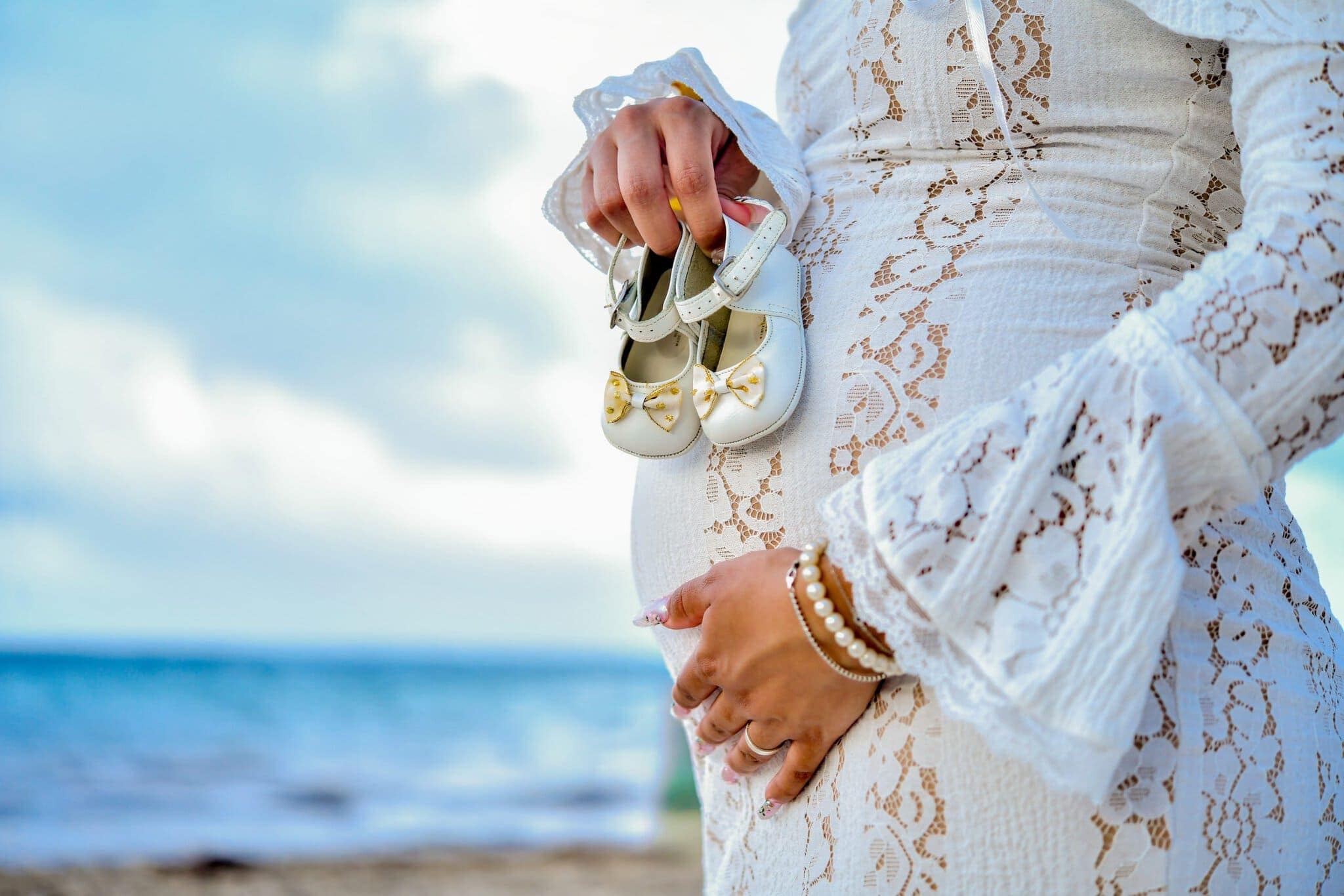 Expectant mother holding a pair of baby shoes beside her baby bump during a maternity session