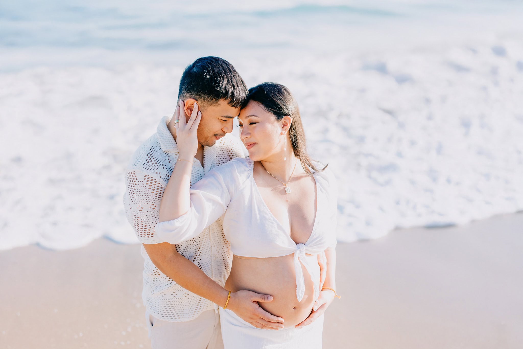 Expecting couple standing forehead to forehead on the beach during a maternity session in Punta Cana