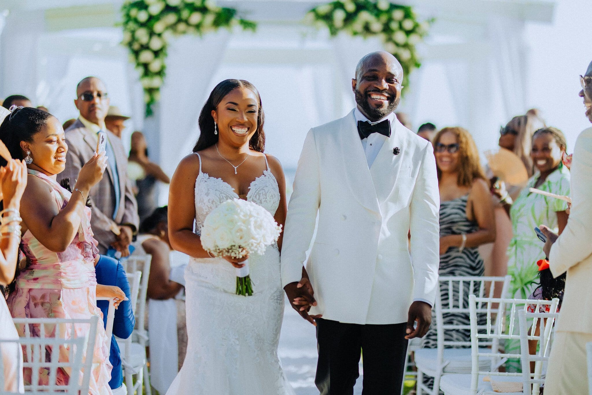 Smiling newlyweds walking down the aisle together as guests celebrate after the ceremony