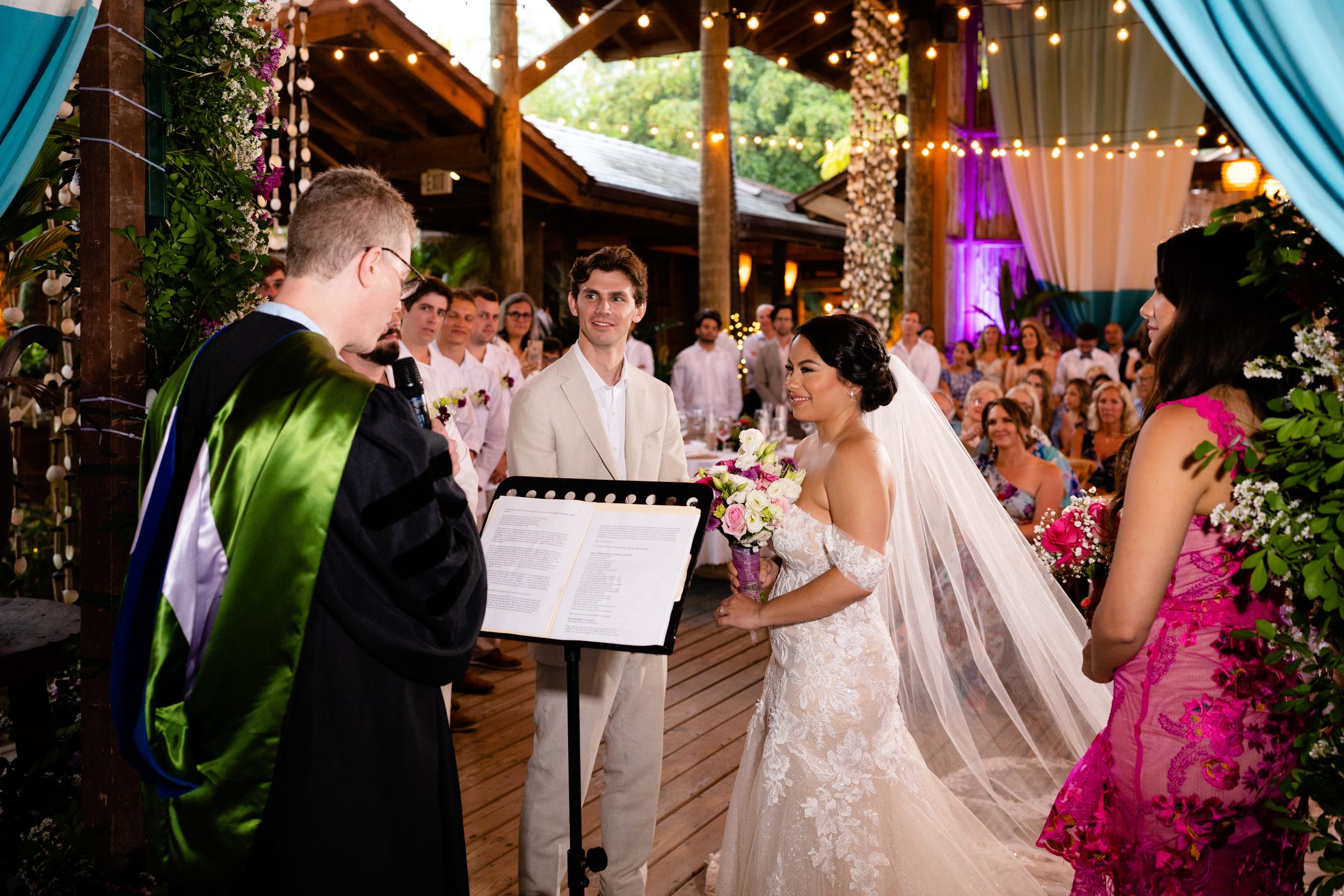 Bride smiling at the groom during their ceremony at Porto by Mosquito in Las Terrenas, surrounded by guests and tropical flowers
