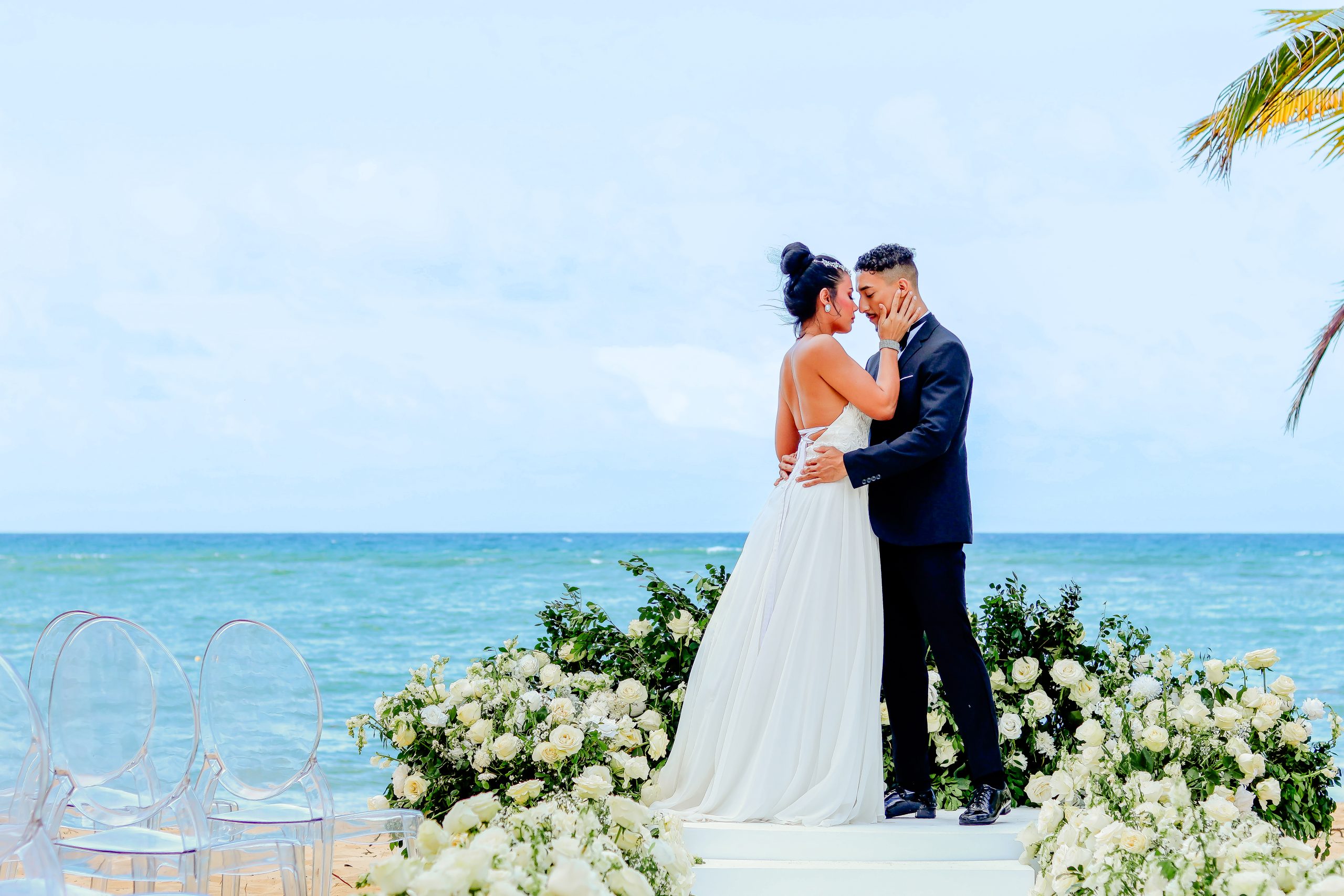 Couple embracing on a white floral altar above the turquoise water during a Punta Cana elopement ceremony