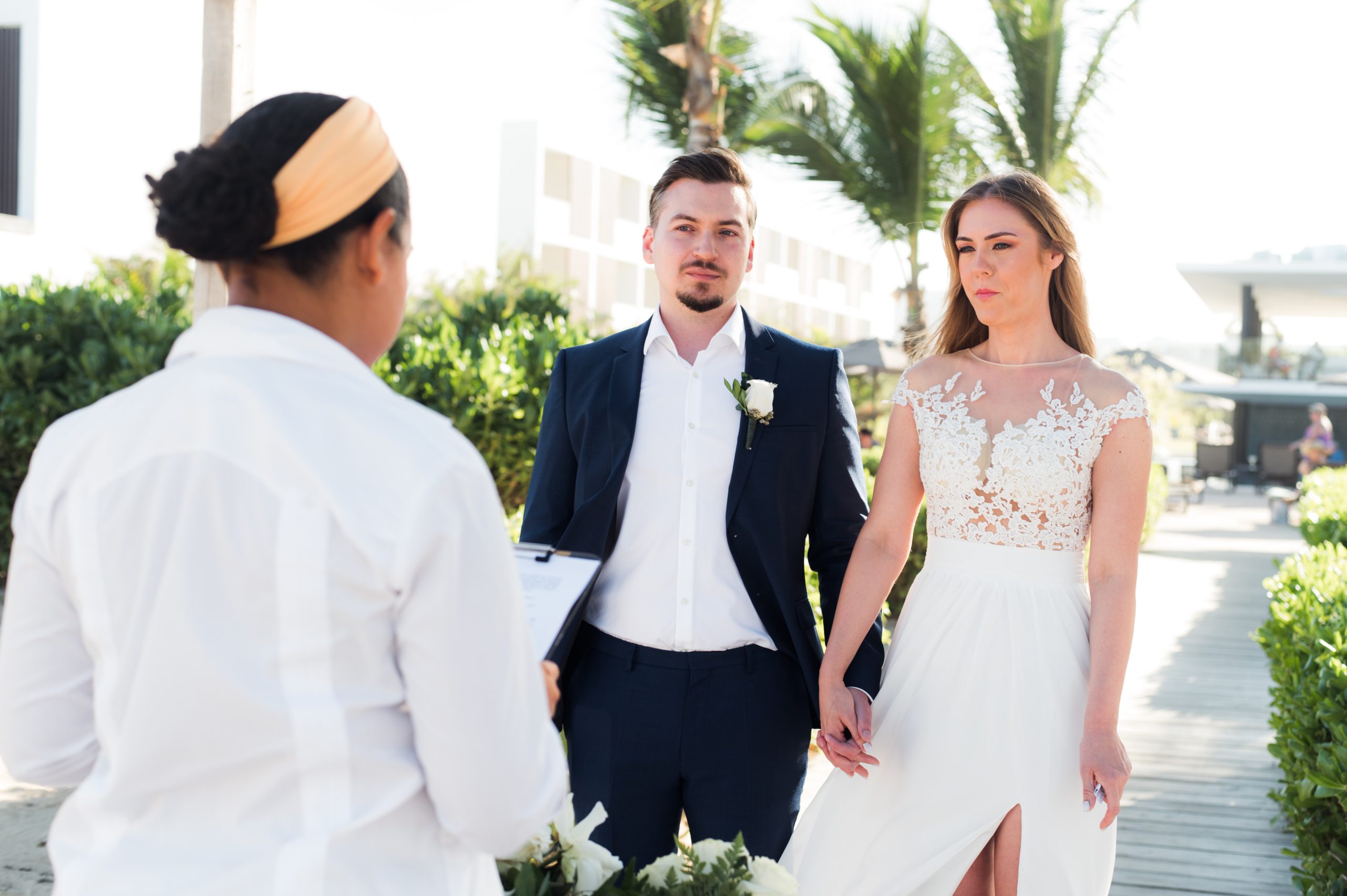 Bride and groom holding hands as they listen to their officiant during a resort elopement ceremony in Punta Cana