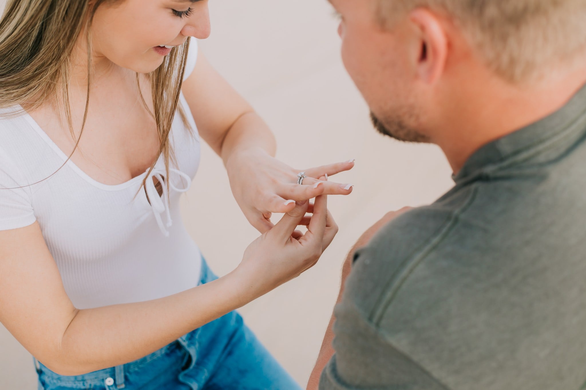 He slides the engagement ring onto her finger as she looks down at her hand
